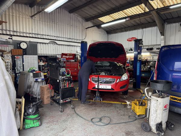 DJ Motors workshop with mechanic working under the bonnet, professional tools and vehicle lifts